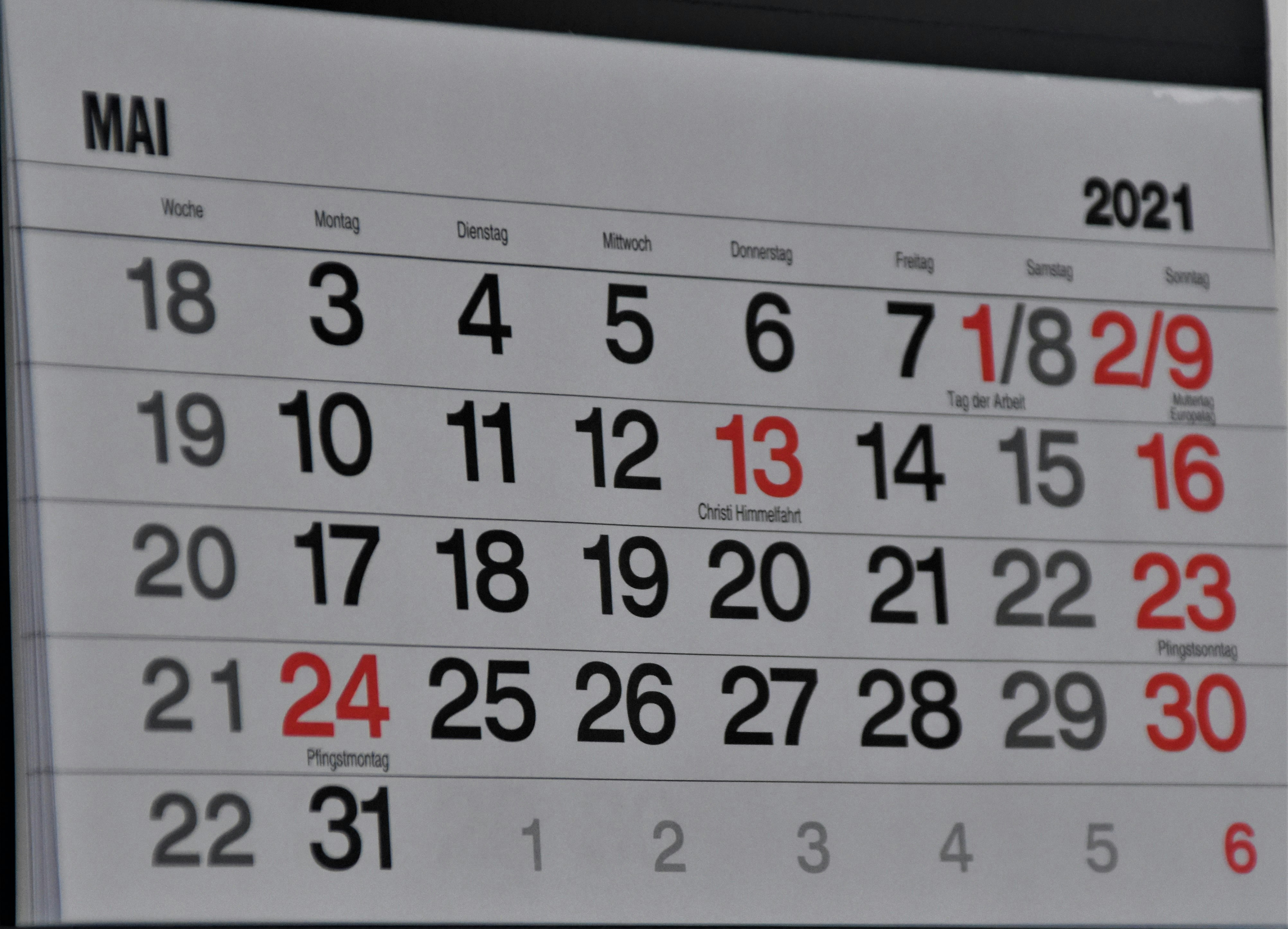 A family kitchen counter showing a tablet with a meal plan and calendar open, next to a bowl of fresh vegetables and a notebook.