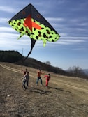 Group of children running on a grassy field flying kites on a sunny day.
