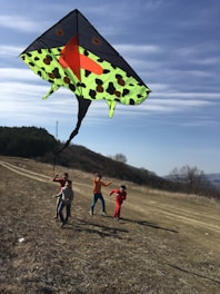 Colorful playful parachute spread out on a grassy field with children holding the edges, smiling and laughing.