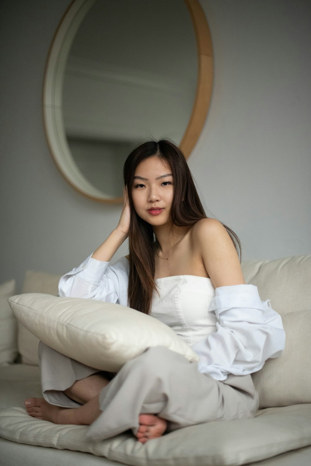 woman in white tube dress sitting on white couch