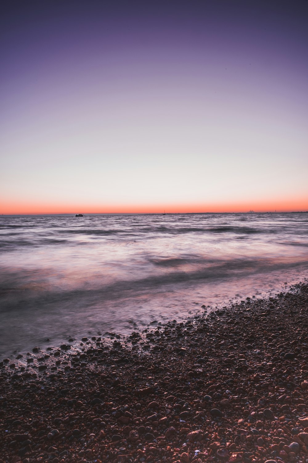 ocean waves crashing on shore during sunset