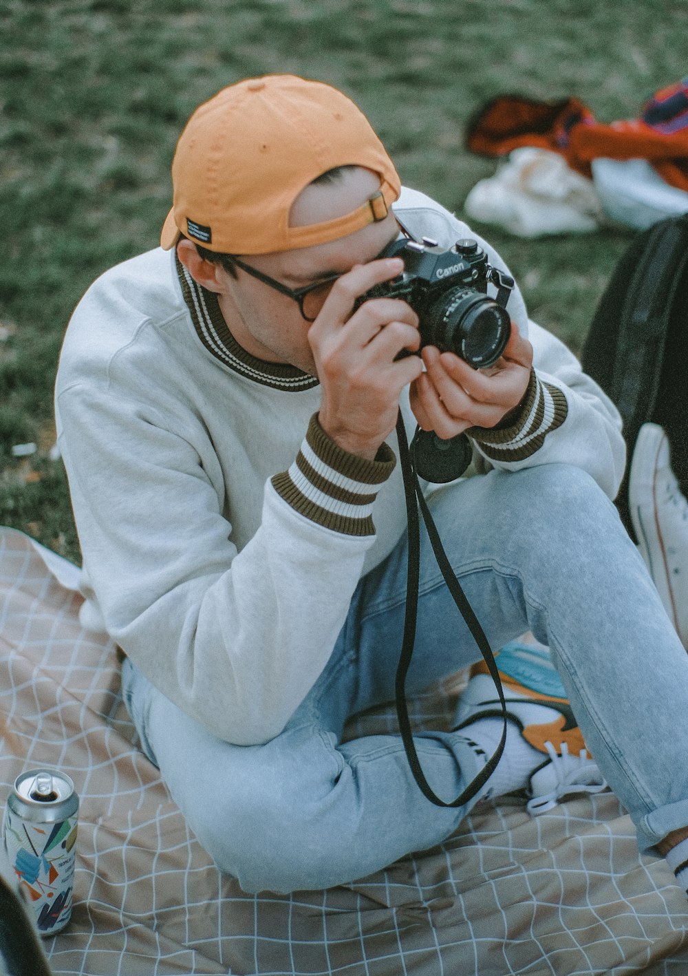 Frau in weißem Pullover und gelber Strickmütze mit schwarzer DSLR-Kamera