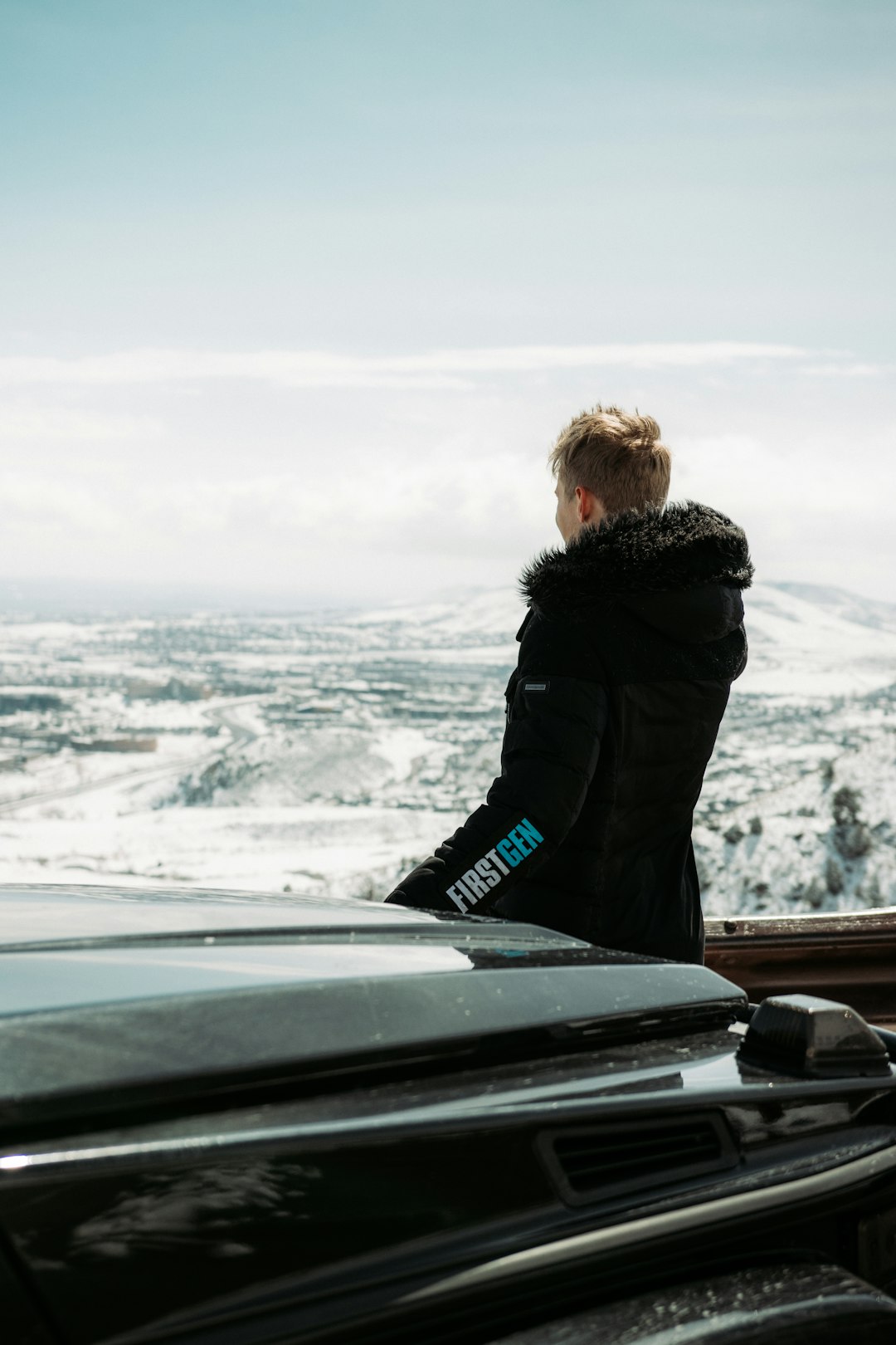 woman in black jacket standing on roof looking at snow covered field during daytime