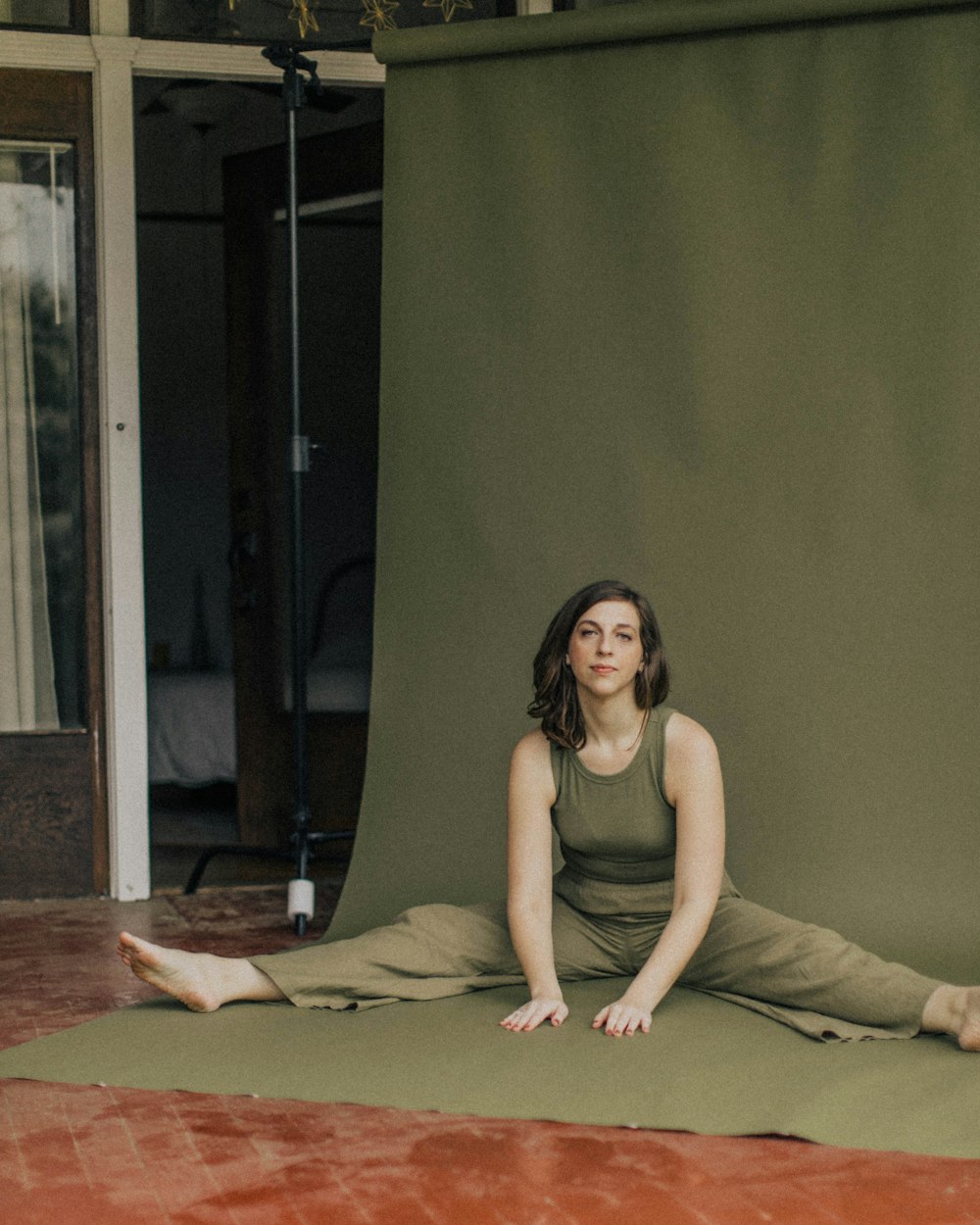 woman in yellow tank top and brown pants sitting on brown wooden floor