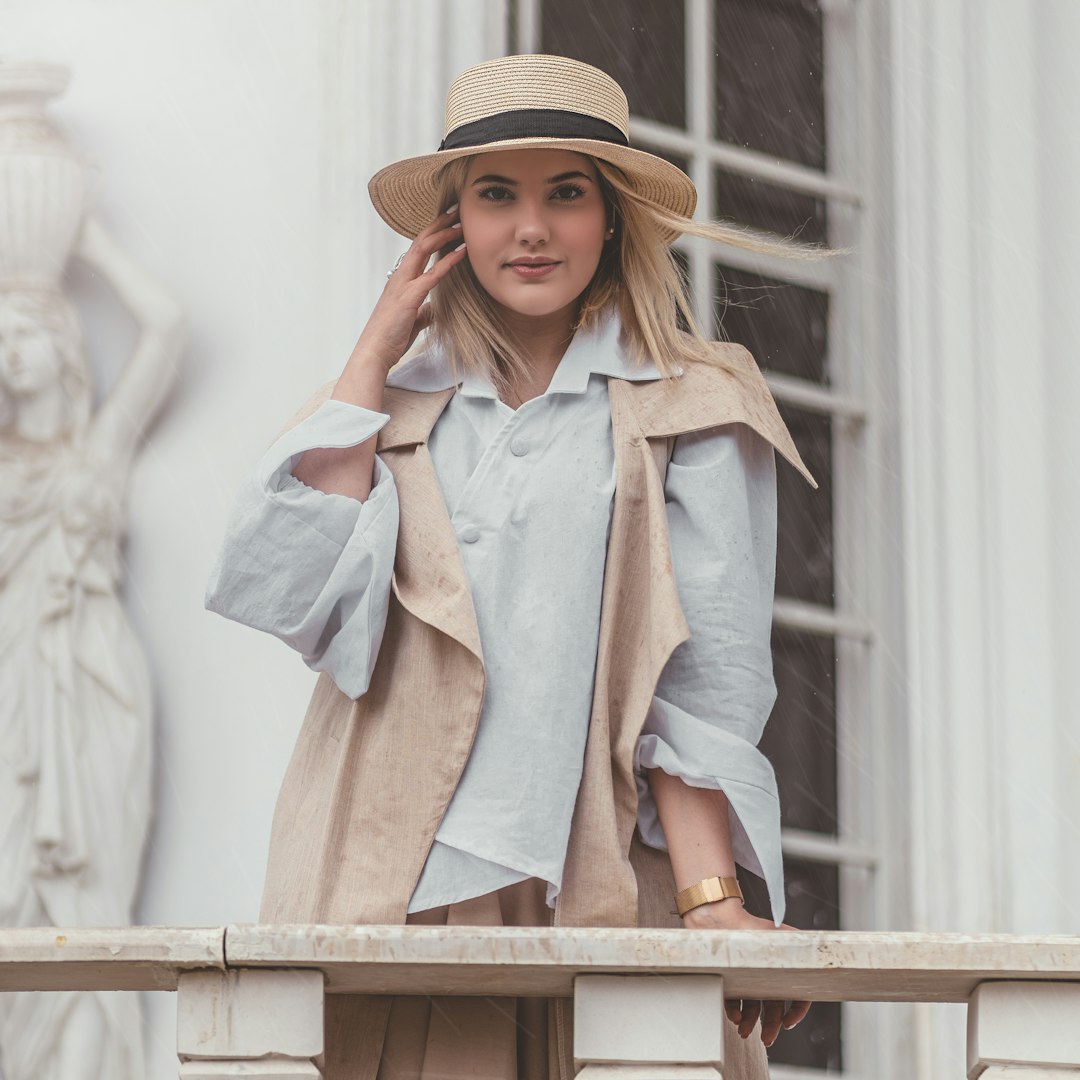 woman in blue button up shirt wearing brown straw hat standing beside brown wooden railings during
