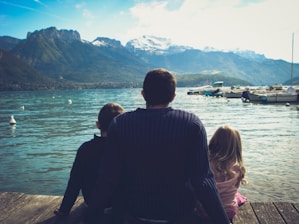 man and woman sitting on brown wooden dock during daytime