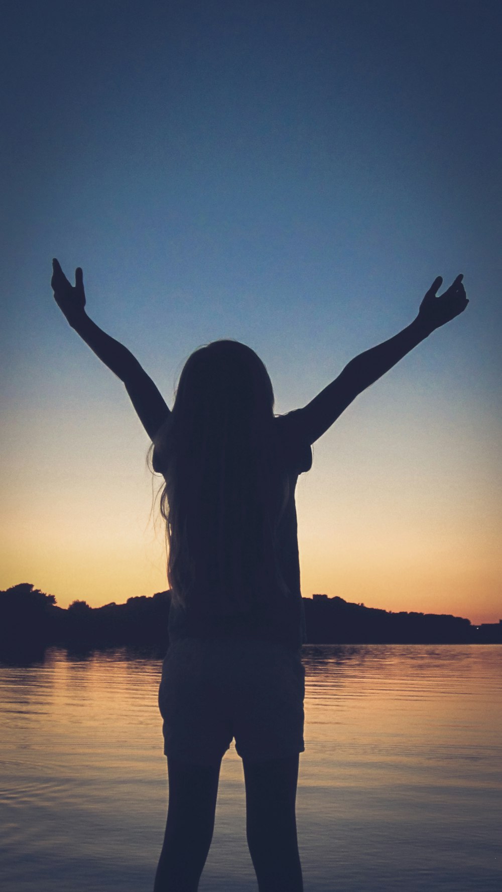 silhouette of woman raising her hands