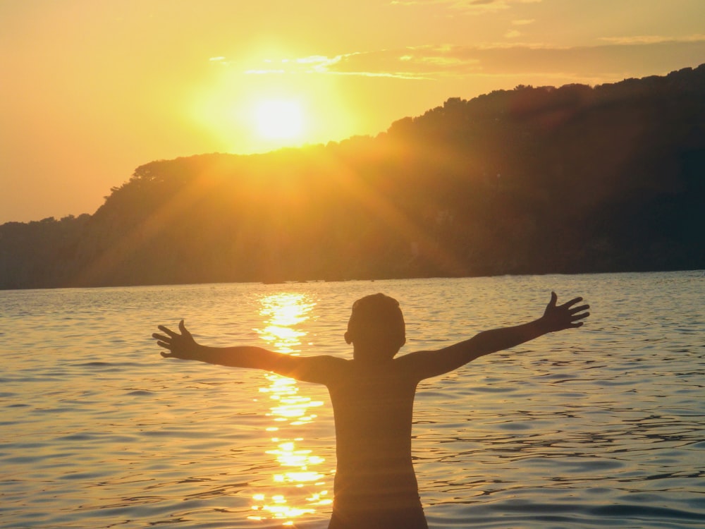 Mujer en el cuerpo de agua durante la puesta del sol