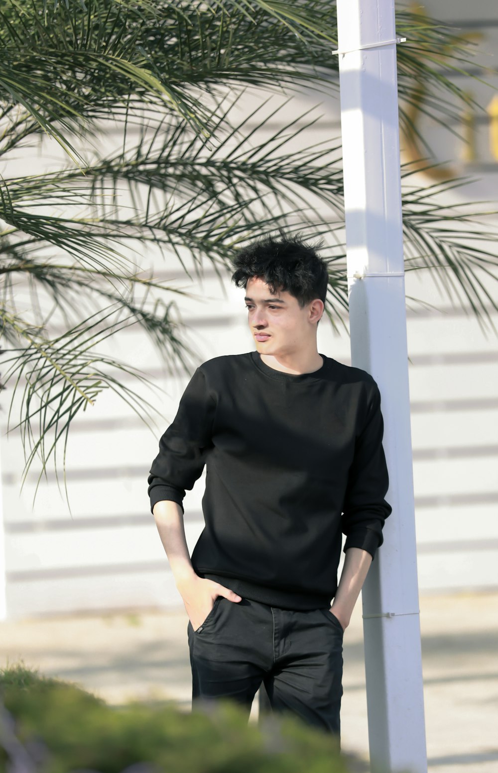 man in black long sleeve shirt standing near white wall