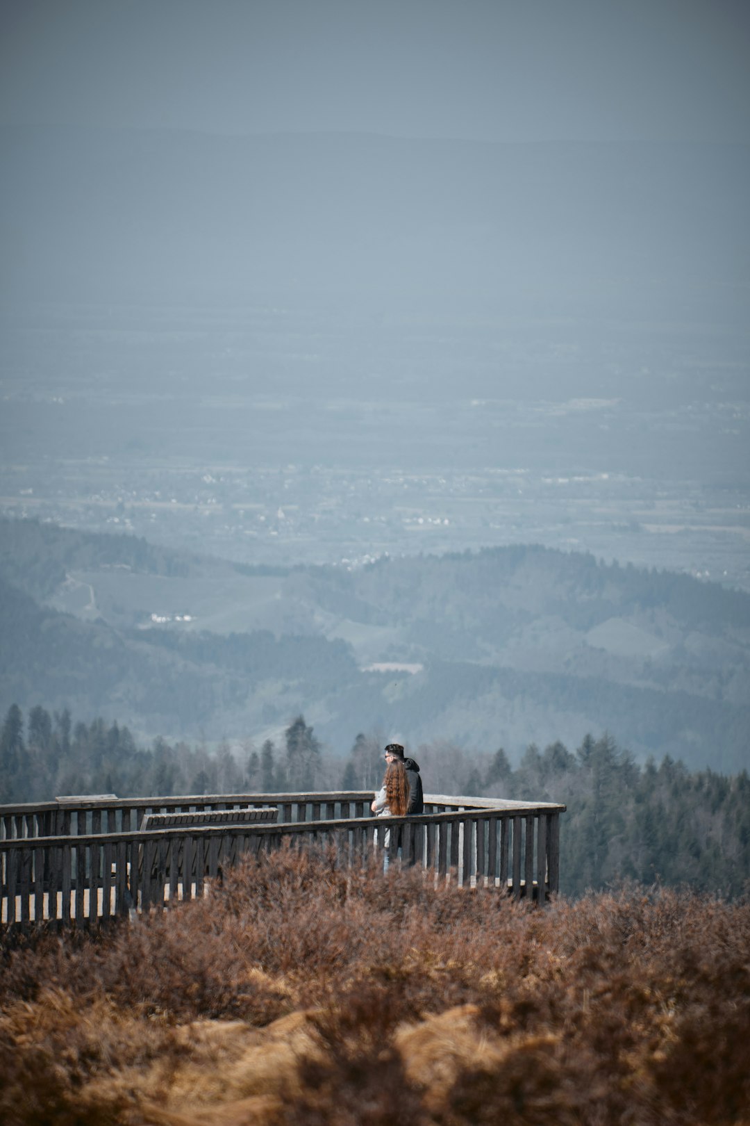 woman in black jacket standing on brown wooden bridge during daytime