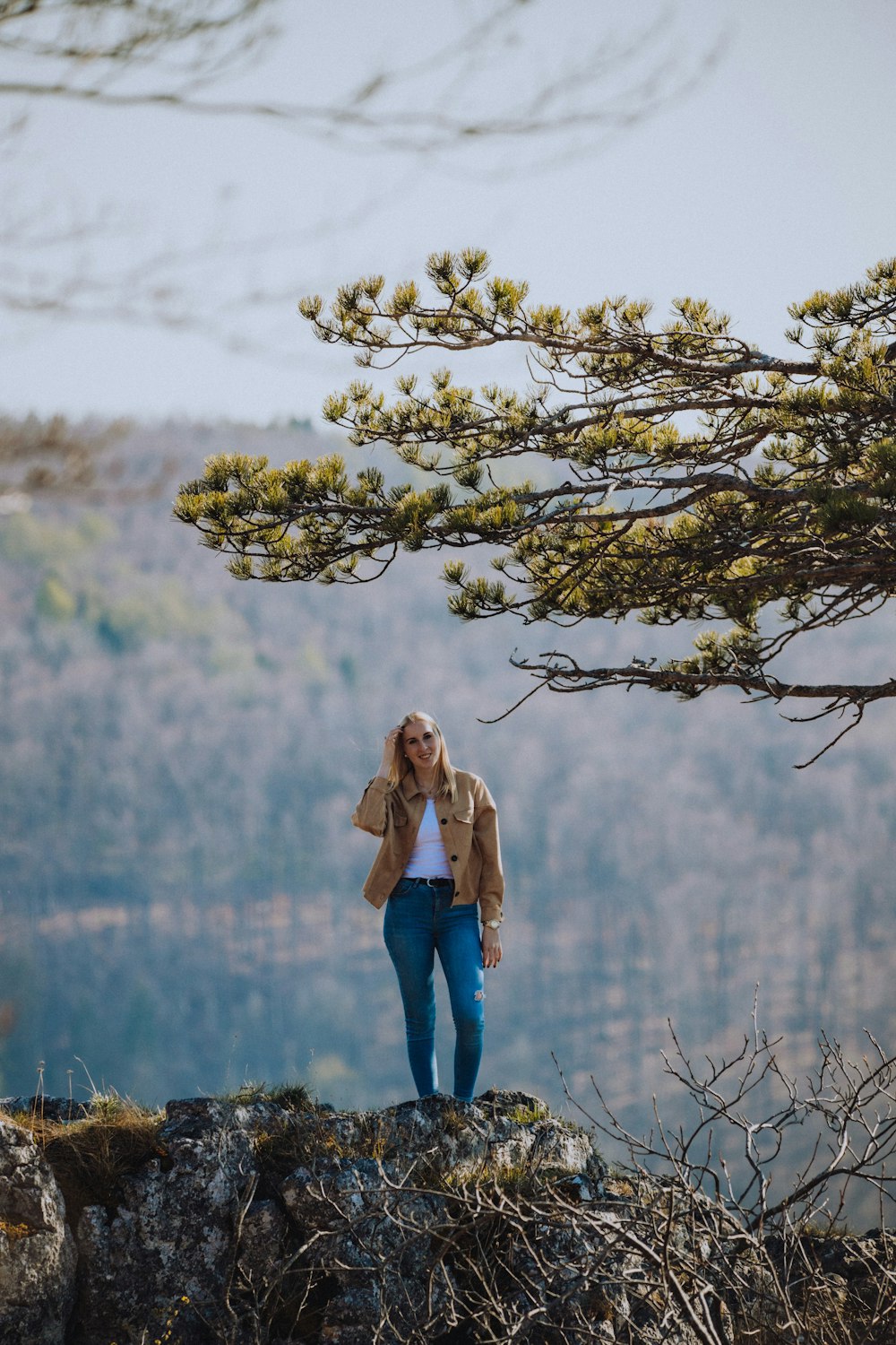 woman in brown coat standing beside white flower tree during daytime