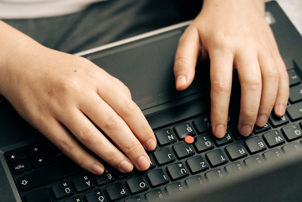 mão de pessoas no teclado preto do computador