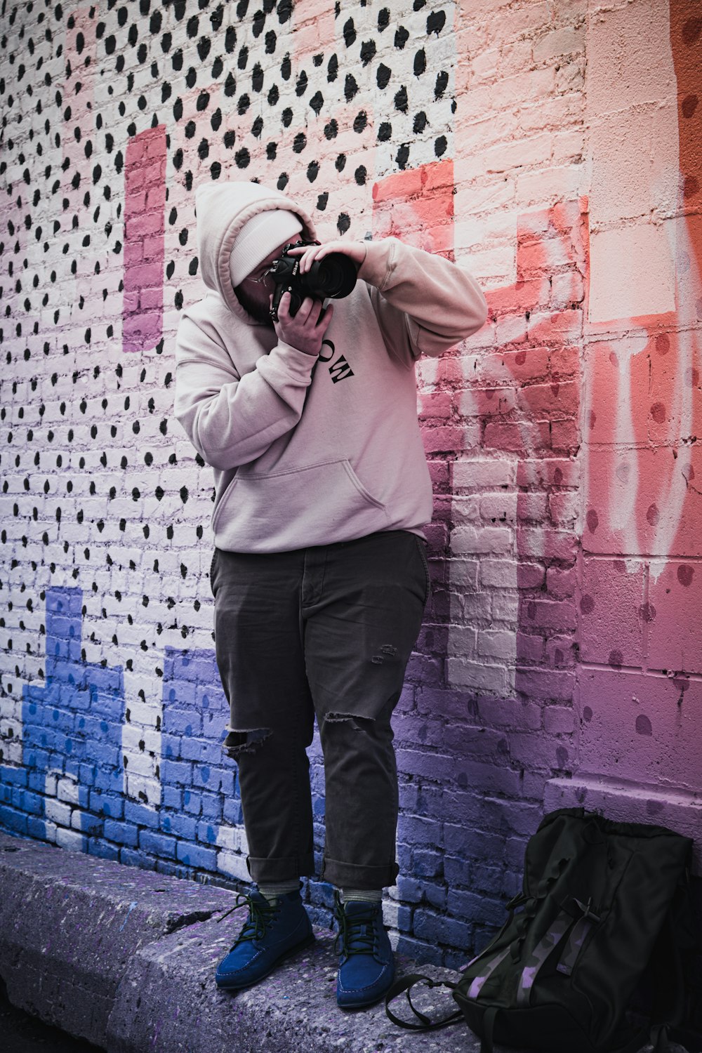 man in pink hoodie and black pants holding camera