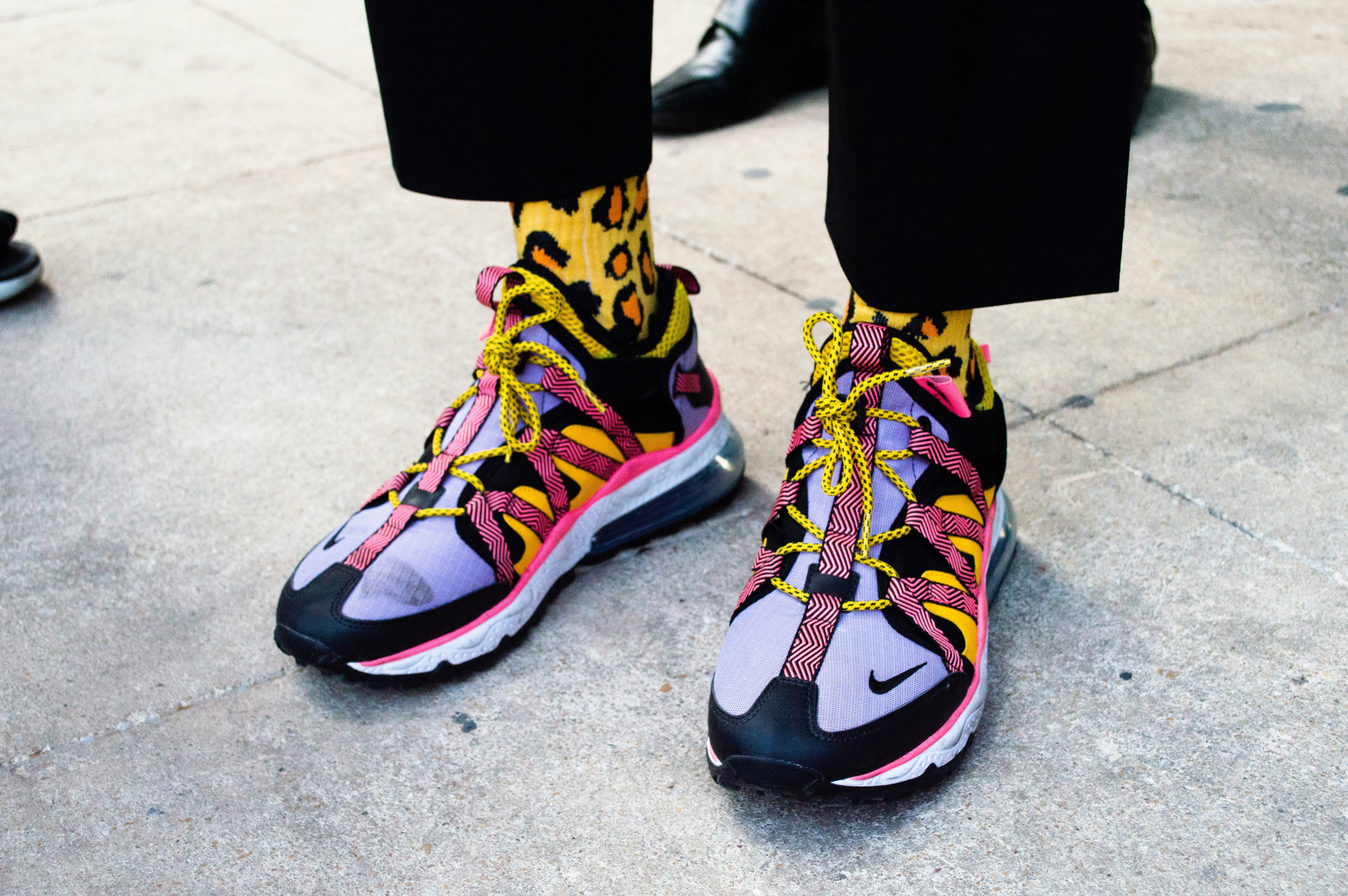 person wearing black blue and yellow nike sneakers