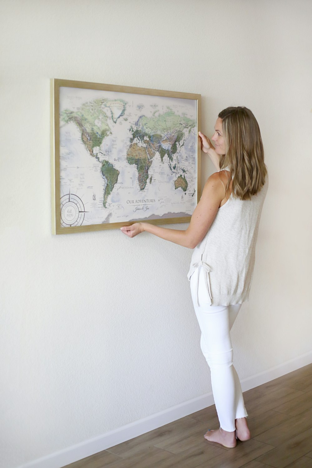 woman in white tank top and white pants standing in front of map