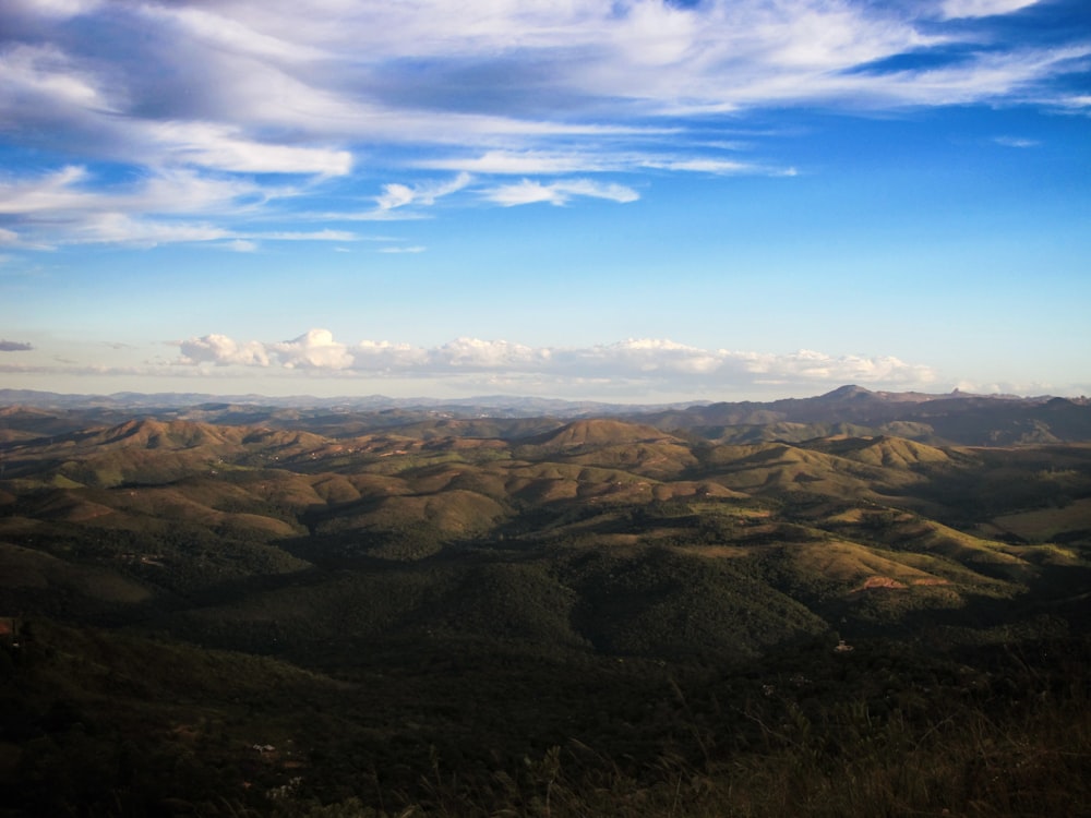 vista aérea de montanhas verdes e marrons sob o céu azul durante o dia