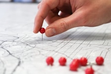 person holding red round medication pill on map