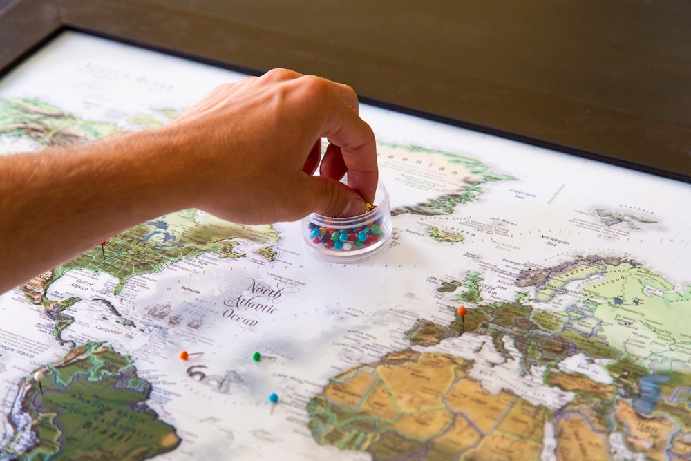 person holding silver ring on white and blue map