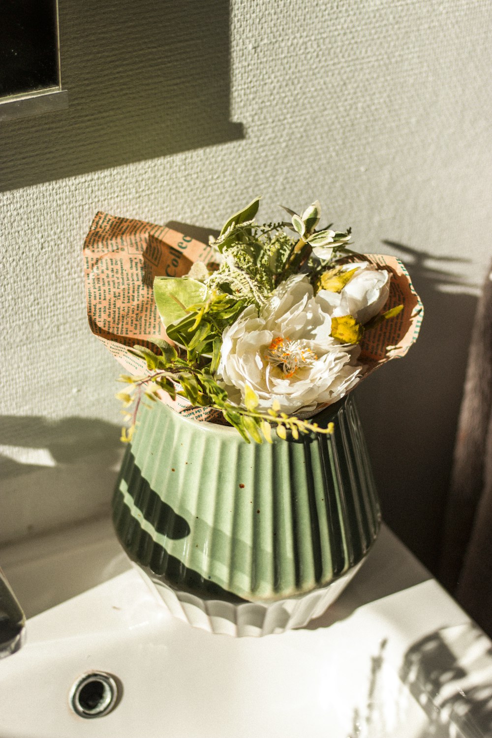 white and yellow flower bouquet in green and white striped vase