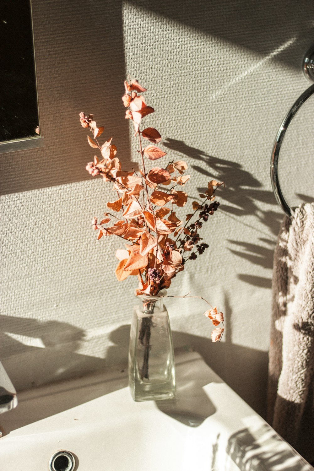 a vase of flowers sitting on a bathroom sink