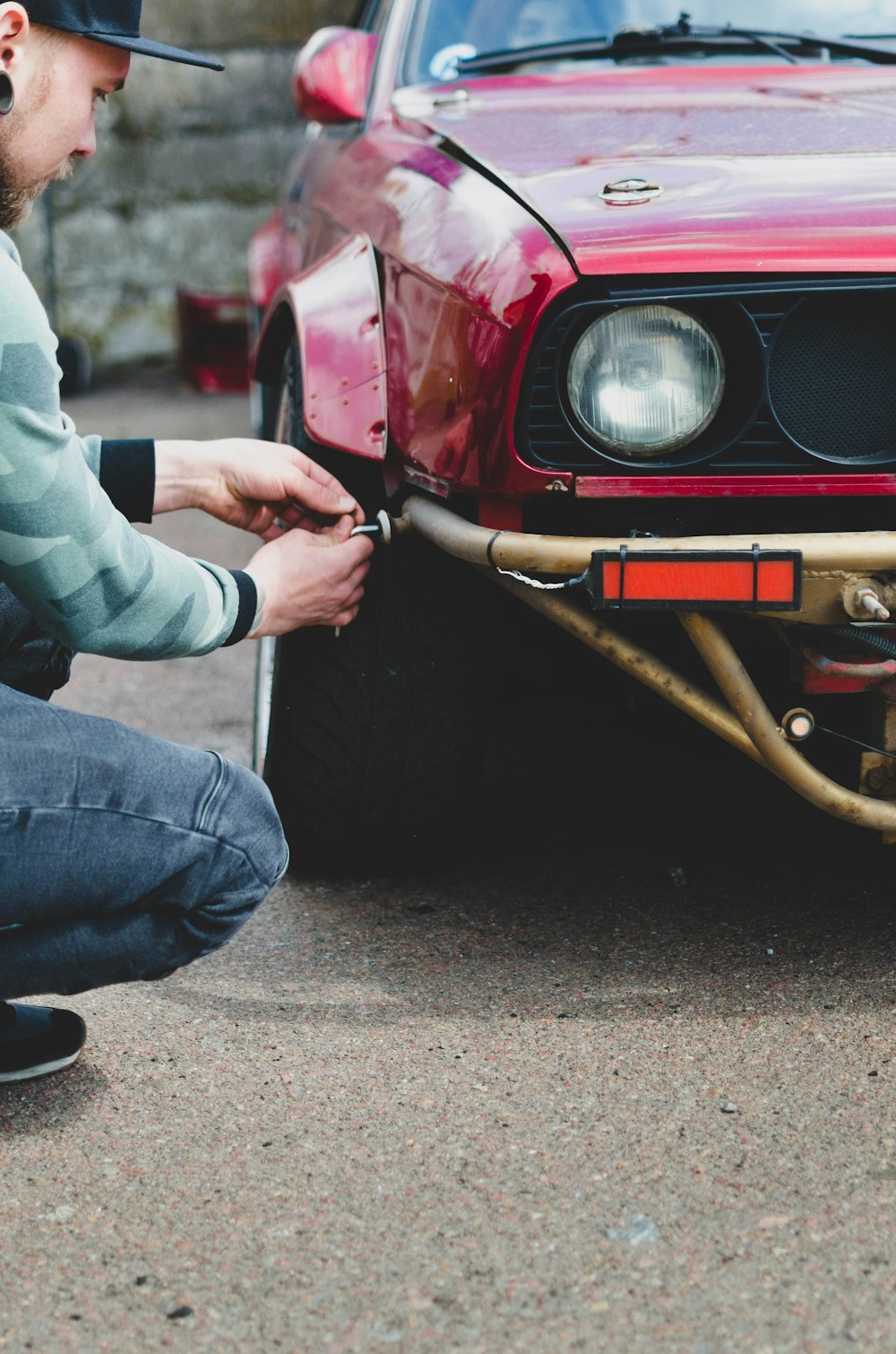 man in gray jacket and blue denim jeans sitting on red car