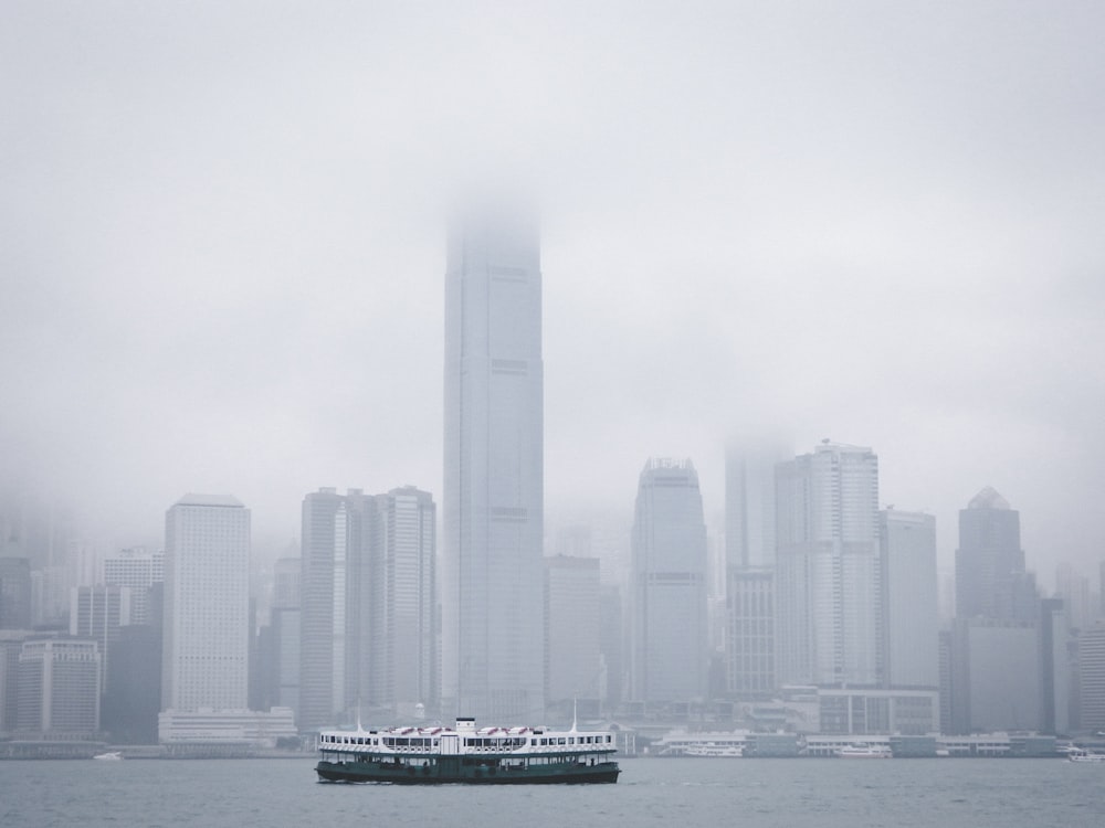 white and black boat on sea near city buildings during daytime