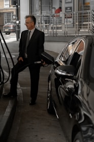 man in black suit standing beside black car