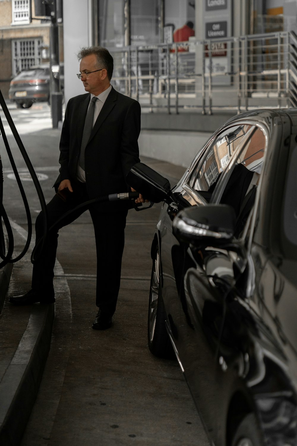 man in black suit standing beside black car