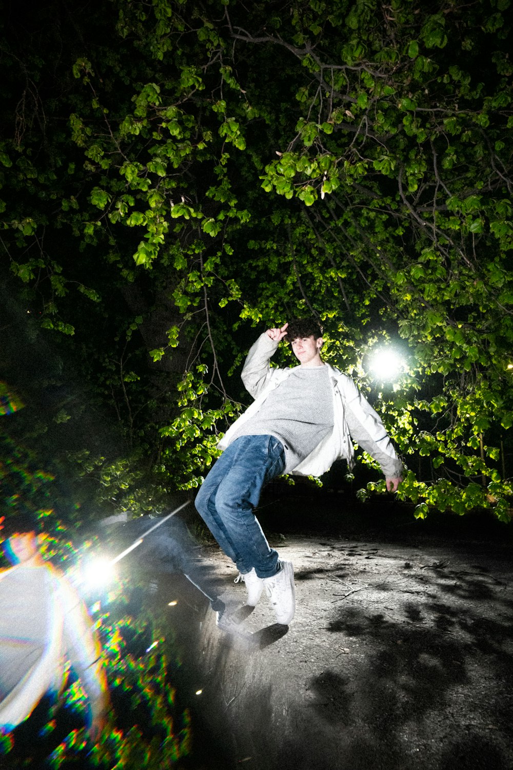 man in white dress shirt and blue denim jeans jumping on the forest during daytime