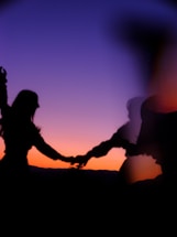 A mystical fiery background with glowing embers surrounding a couple holding hands in silhouette.