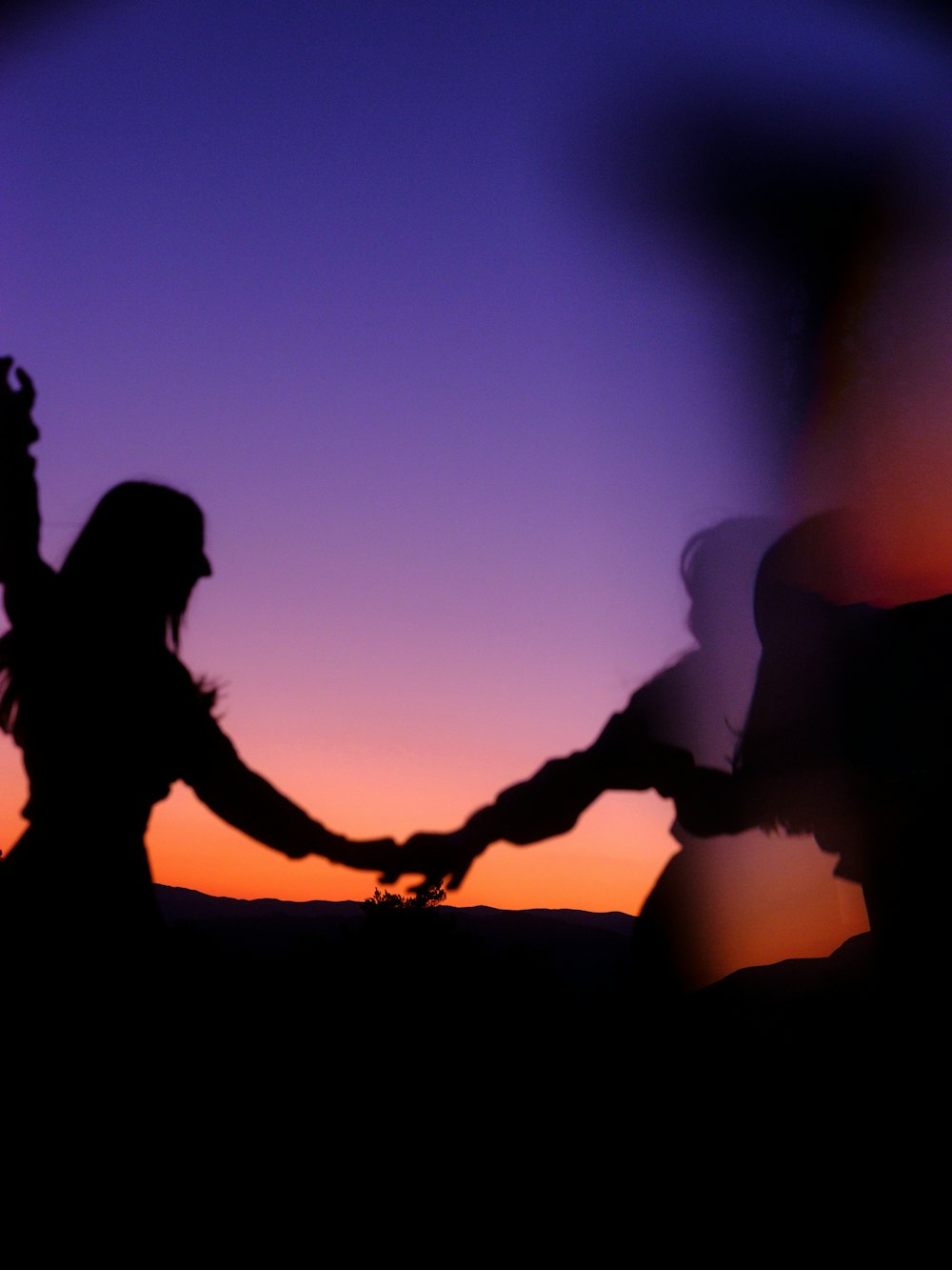 silhouette of 2 women sitting on ground during sunset