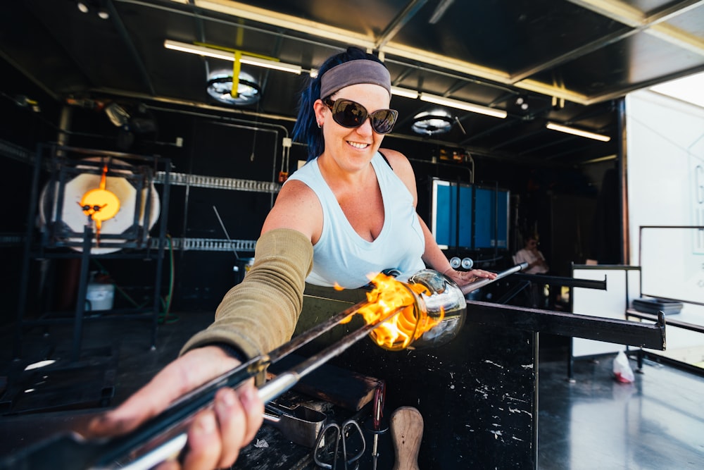 man in white tank top holding a stick with fire