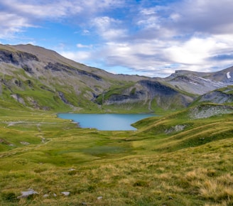 green and brown mountains beside lake under blue sky during daytime