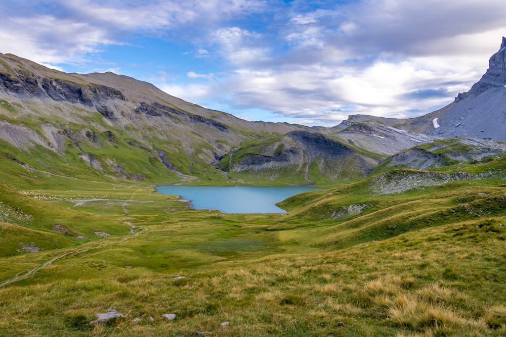 green and brown mountains beside lake under blue sky during daytime