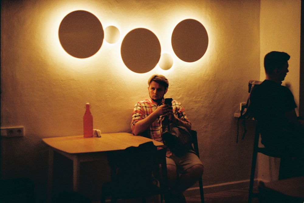 man in brown and white plaid dress shirt sitting on chair