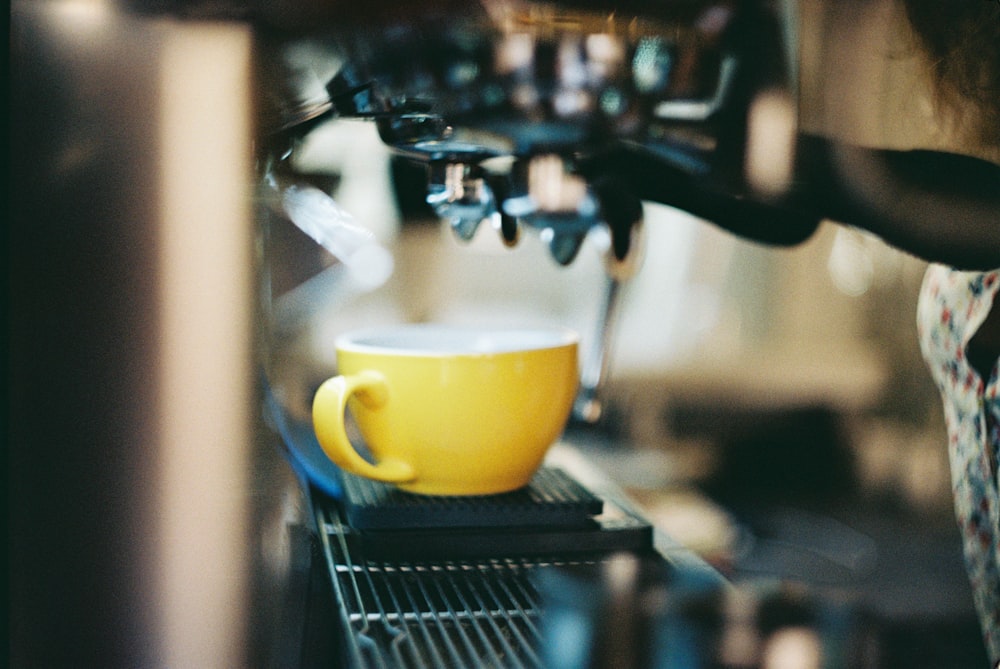 yellow ceramic mug on black and silver espresso machine