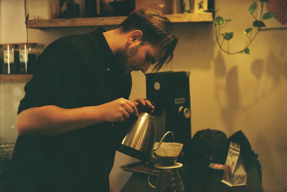 man in black shirt holding black and silver coffee maker