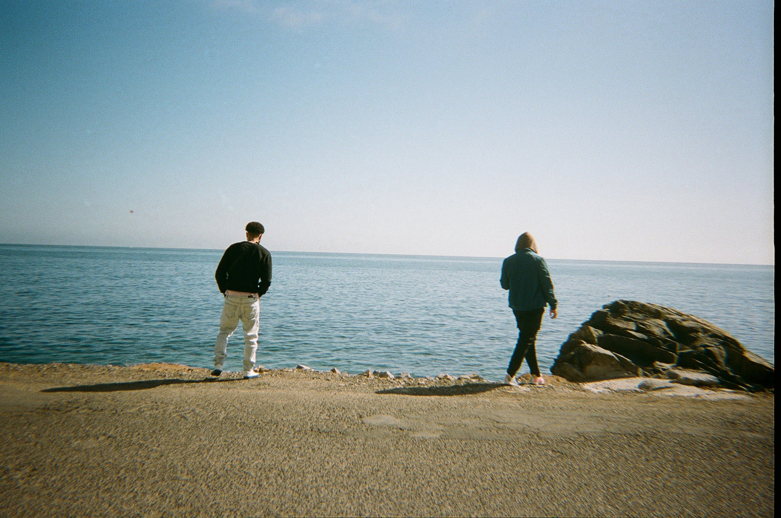 man and woman walking on beach during daytime
