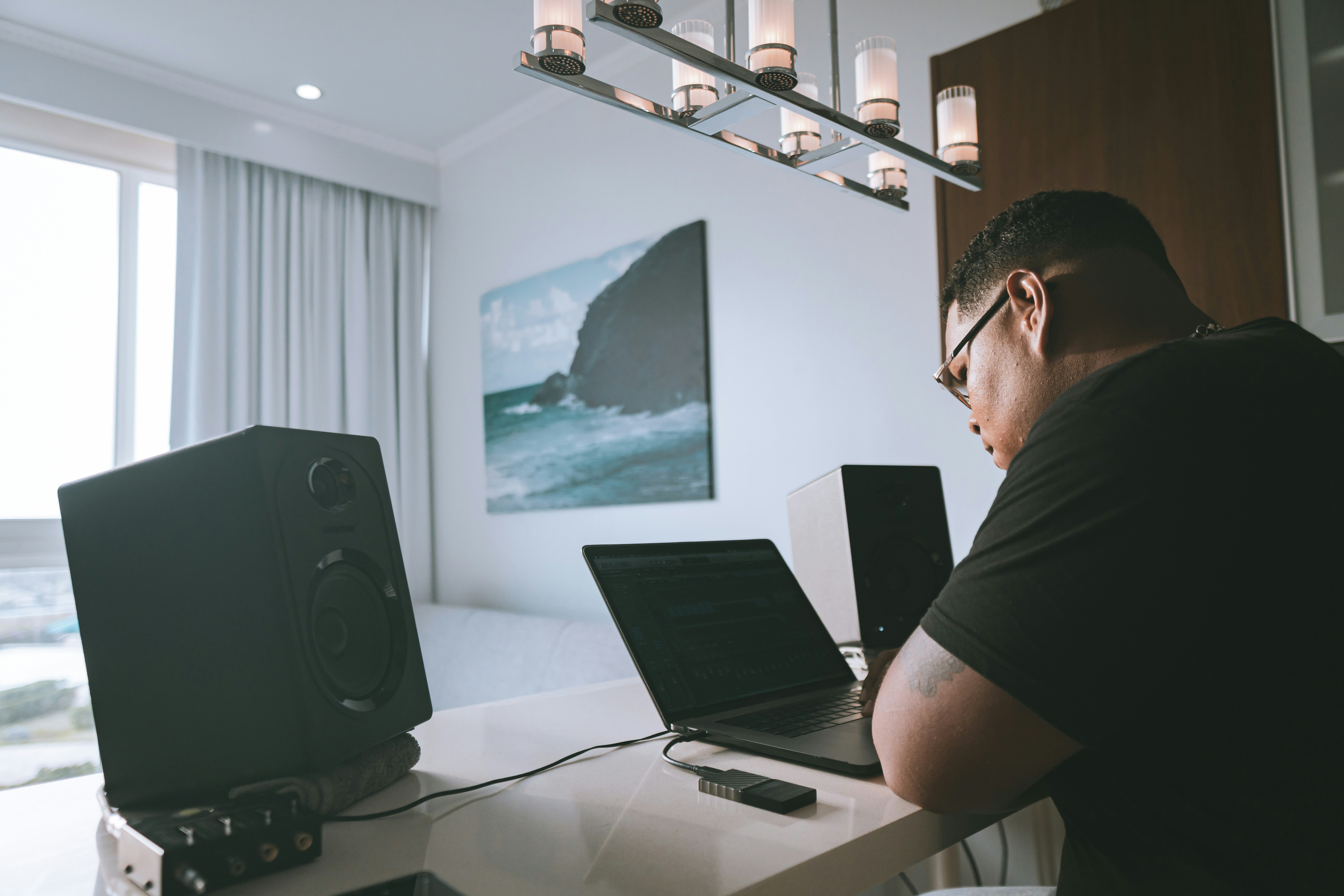 man in black t-shirt sitting in front of macbook pro
