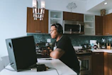 Lifestyle shot of a person working on a laptop in a bright, modern farmhouse kitchen.