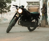 A close-up of a vintage motorcycle parked under warm streetlights at dusk.