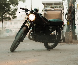 A close-up of a vintage motorcycle parked under warm streetlights at dusk.