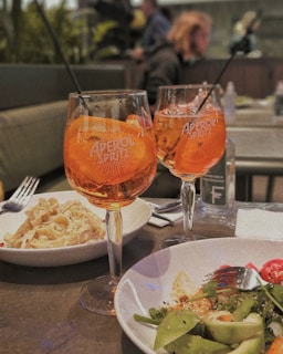 A colorful aperitivo spread with small bites and glasses of spritz on a rustic wooden table.