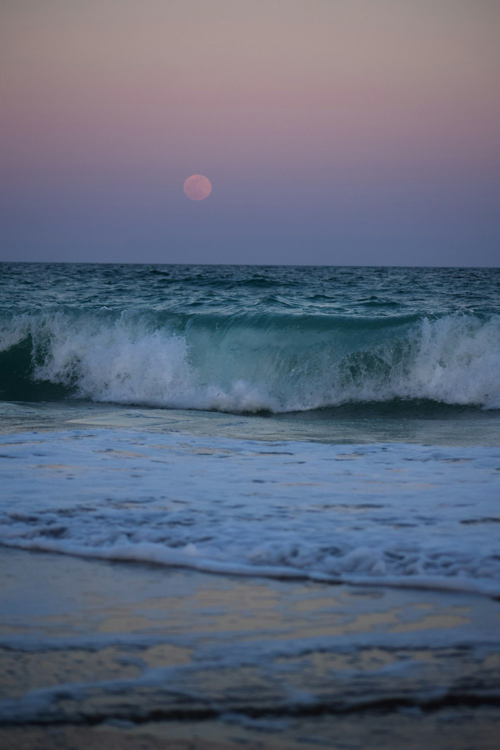 ocean waves crashing on shore during sunset