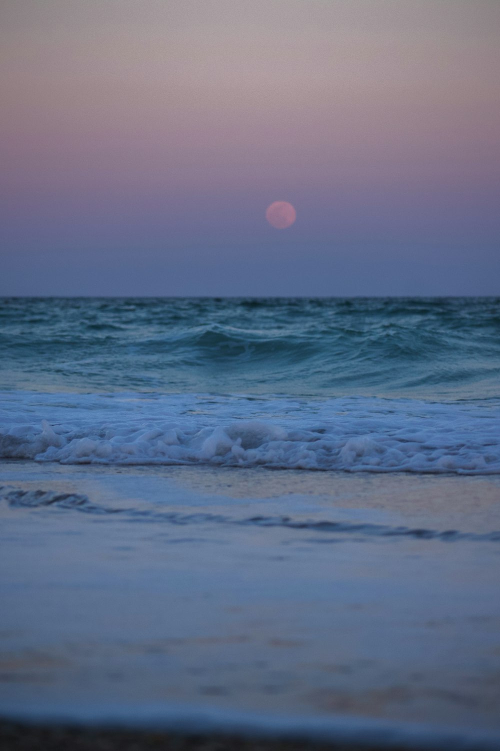 ocean waves crashing on shore during sunset