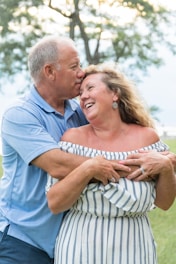 Older man in blue polo kissing woman in striped shirt, symbolizing older male HIV prevention