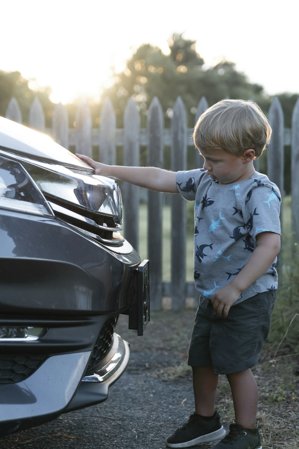 boy in blue t-shirt standing beside black car during daytime