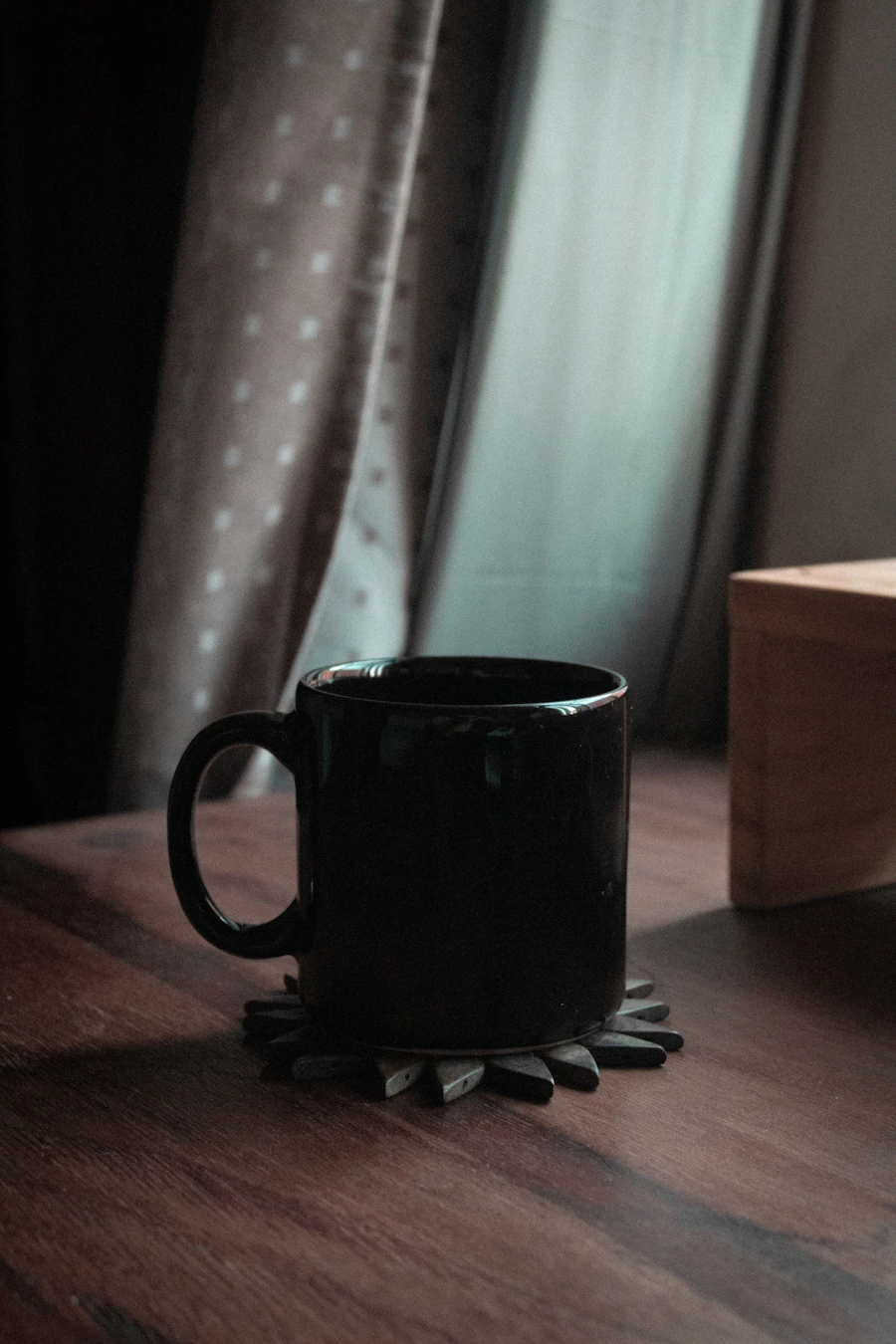 Black mug on a wooden table by a window