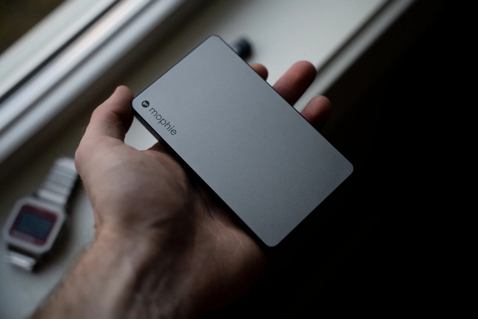 Hand holding a slim portable power bank, a helpful backup while learning how to improve phone battery life