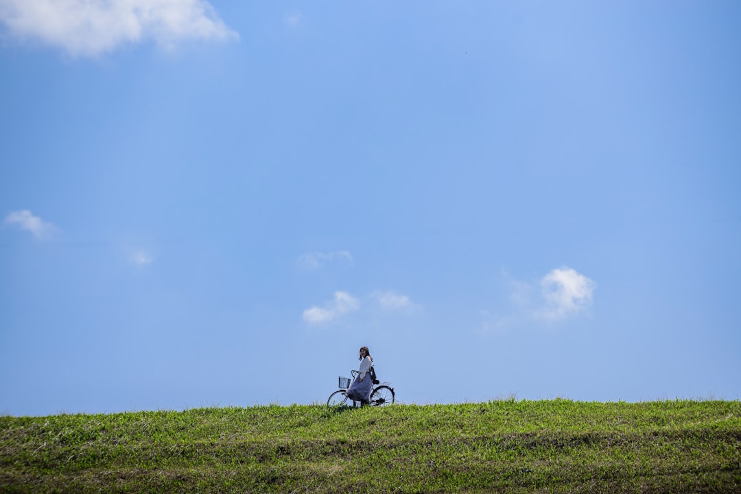 man in black jacket sitting on green grass field under blue sky during daytime